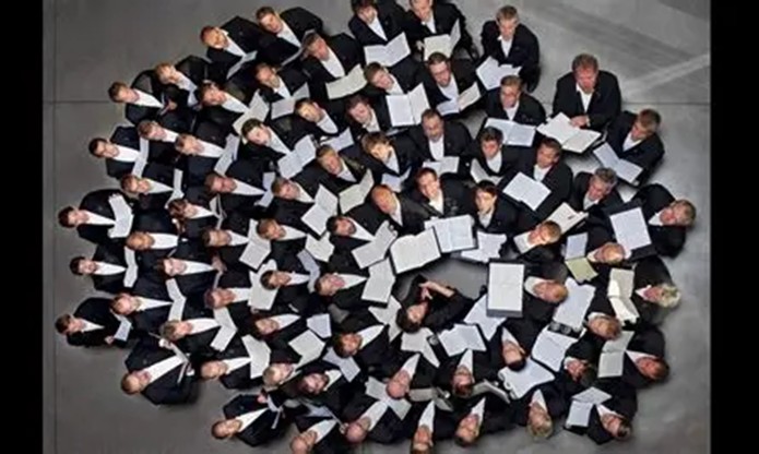 A large choir photographed from above, scores in hand